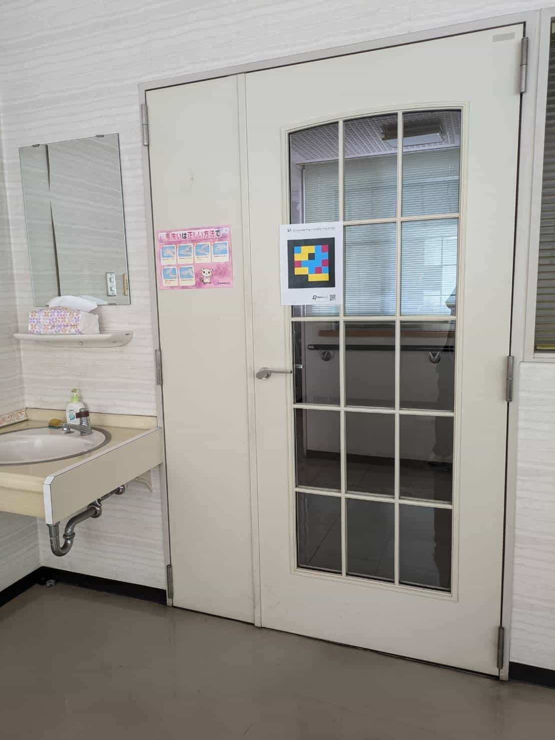 Door of the toilet at Abe Eye Clinic with NaviLens Public Kit code placed at eye level
