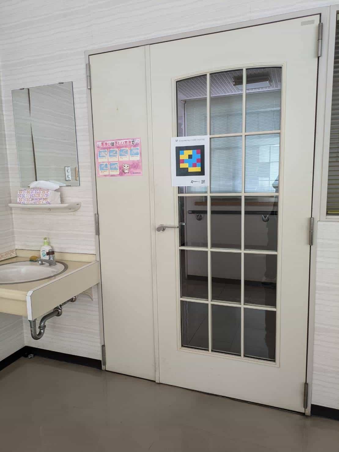 Toilettentür der Abe Eye Clinic mit NaviLens-Public-Kit-Code auf Augenhöhe angebracht