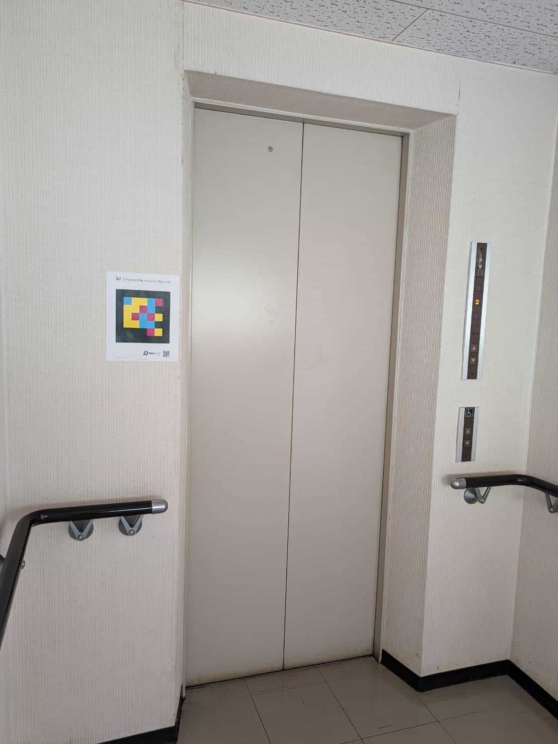 NaviLens-Code aus dem Public Kit neben dem Aufzug der Abe Eye Clinic in Oita, Japan