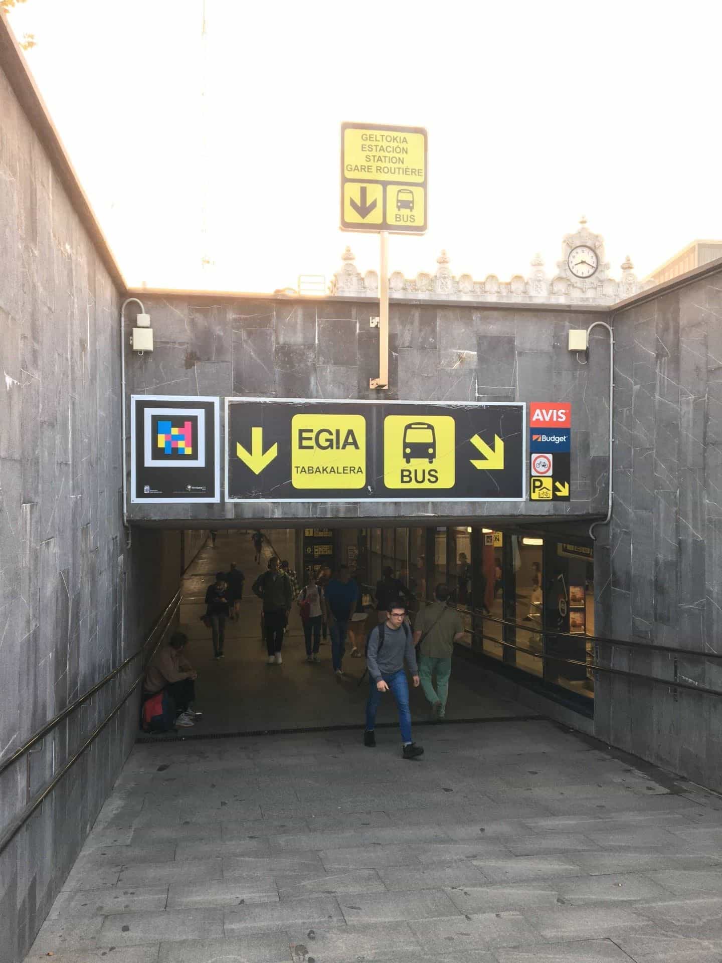 Accesso pedonale alla stazione degli autobus di Donostia con cartello NaviLens accanto alle frecce gialle Egia Tabakalera e Bus