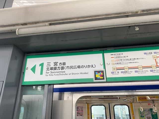 1番線の緑色サイン「1 三宮方面・北埠頭方面(市民広場のりかえ)」、右下隅にNaviLensタグ。下にはポートライナーのホームドアが開いている