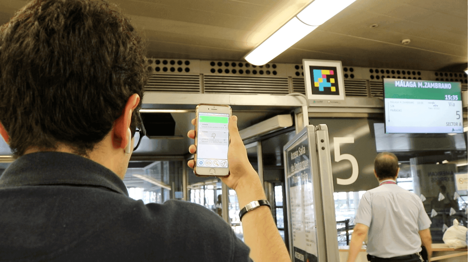Voyageuse détectant une signalétique NaviLens dans le hall d’une gare ferroviaire