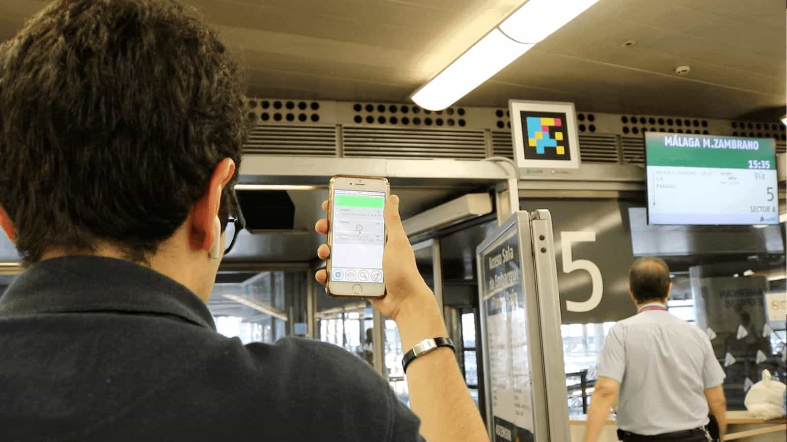 Viaggiatrice che rileva la segnaletica NaviLens nell’atrio di una stazione ferroviaria
