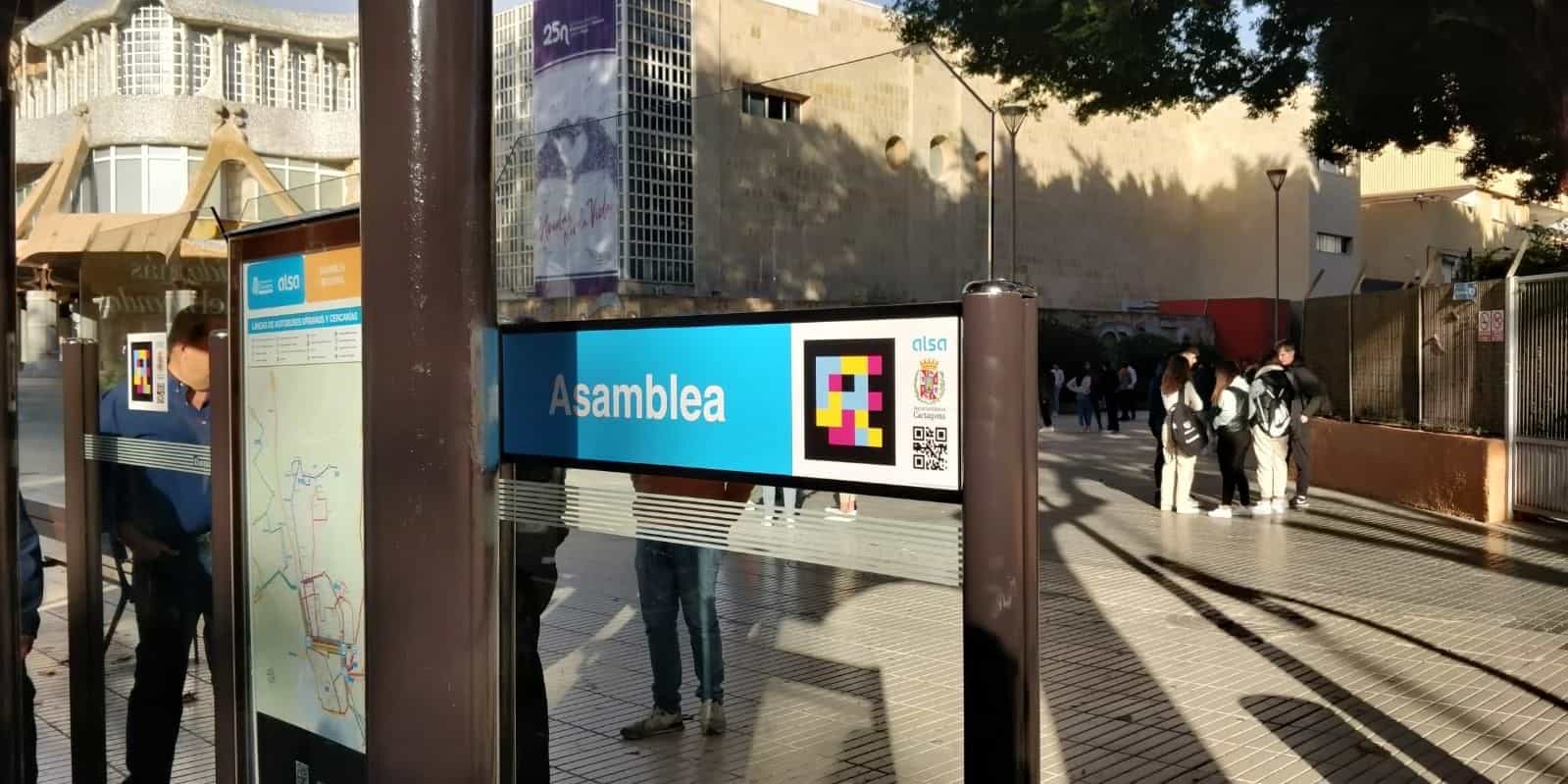 Cartello blu «Asamblea» della fermata del bus di Cartagena con un grande codice NaviLens e i logo di ALSA e del Comune di Cartagena