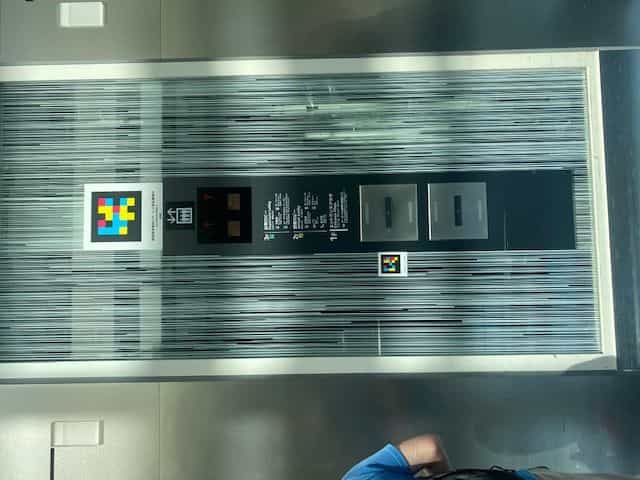Glasaufzug am Haneda T3 mit zwei NaviLens-Codes und Stockwerksverzeichnis