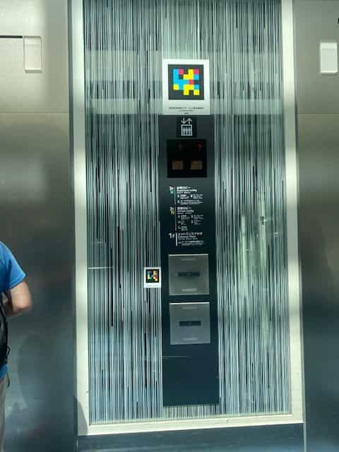 Haneda T3 glass elevator with two NaviLens codes and floor directory