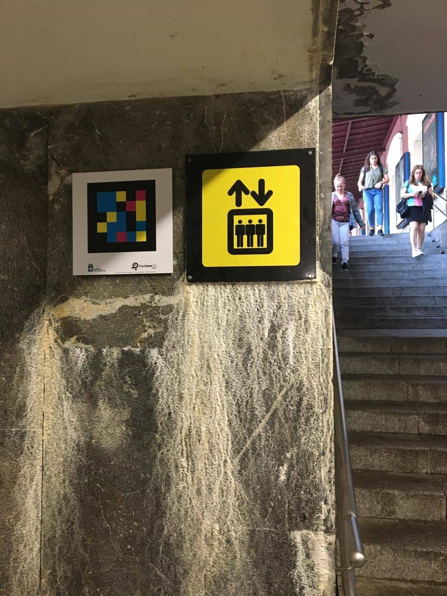 Yellow lift pictogram on a marble column with a NaviLens NaviLensGO code