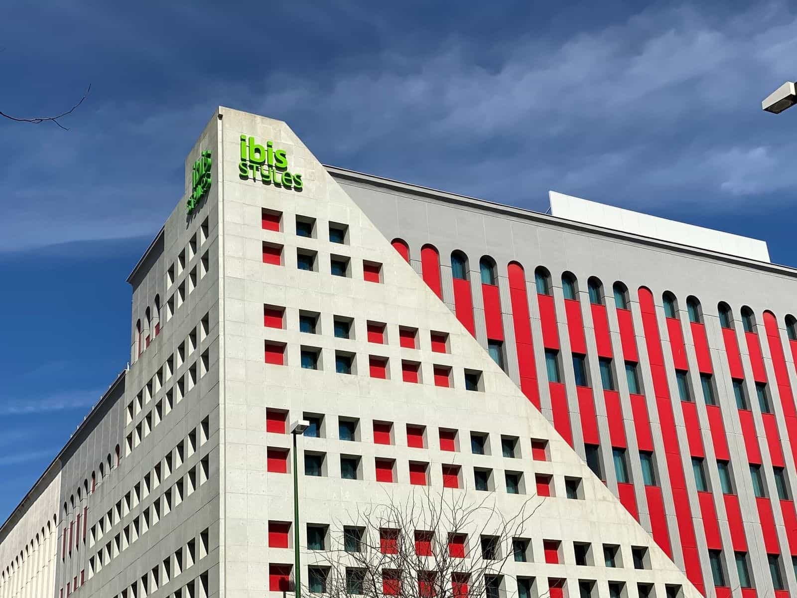 Aufzug am ibis Styles Sevilla mit offener Kabine, grün belaubter Tapete und einem orangen Disc mit „N1“-Piktogramm, darunter ein NaviLens-Code
