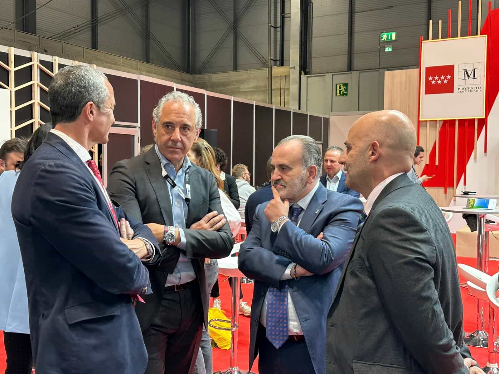 Quattro responsabili istituzionali di Decanta Madrid conversano nello stand della Comunità di Madrid al Salón Gourmets di IFEMA, accanto al pannello rosso «M Producto Certificado» della Comunità di Madrid