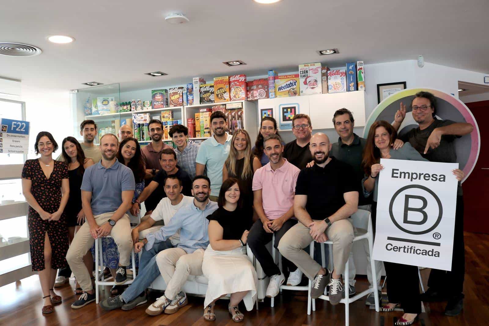 Das NaviLens-Team im Büro in Murcia mit dem Schild „Empresa B Certificada“; im Hintergrund Verpackungen von Kellogg’s, Weetabix und anderen Marken mit NaviLens-Code