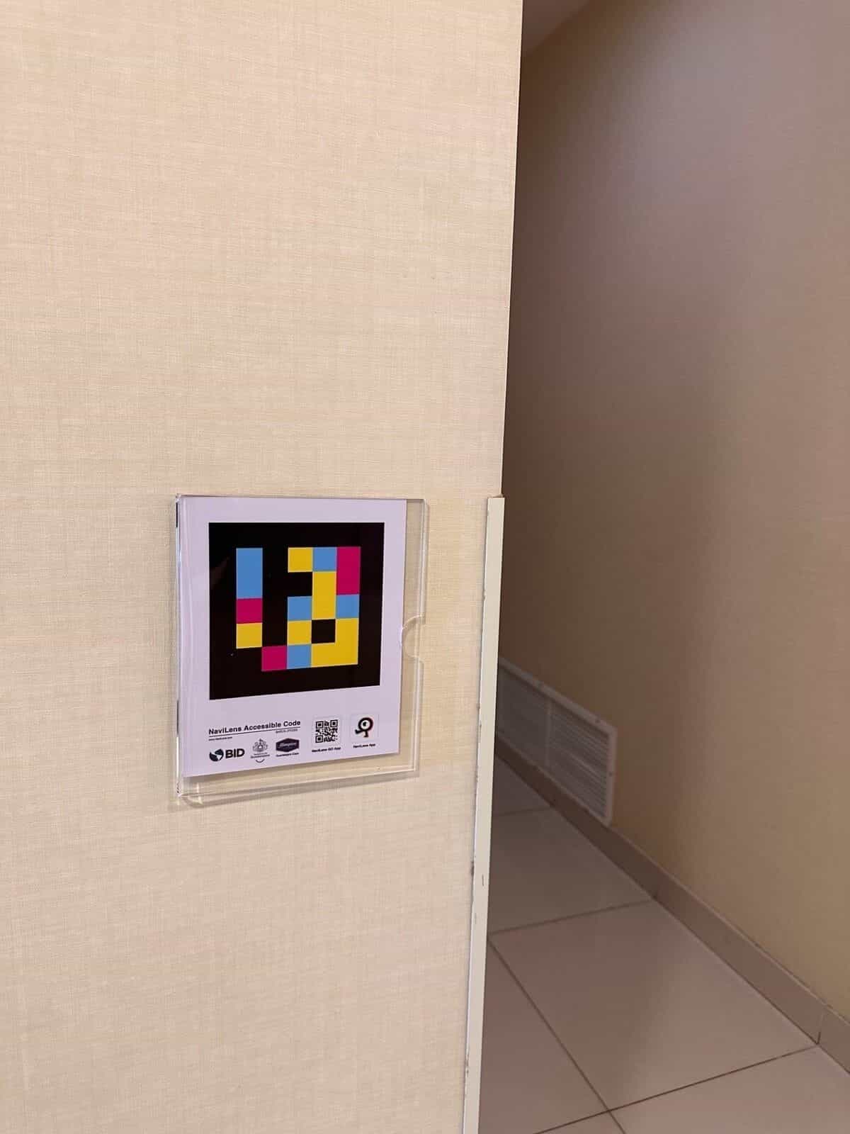 Panneau NaviLens dans le couloir d'accès aux toilettes de l'Hampton by Hilton