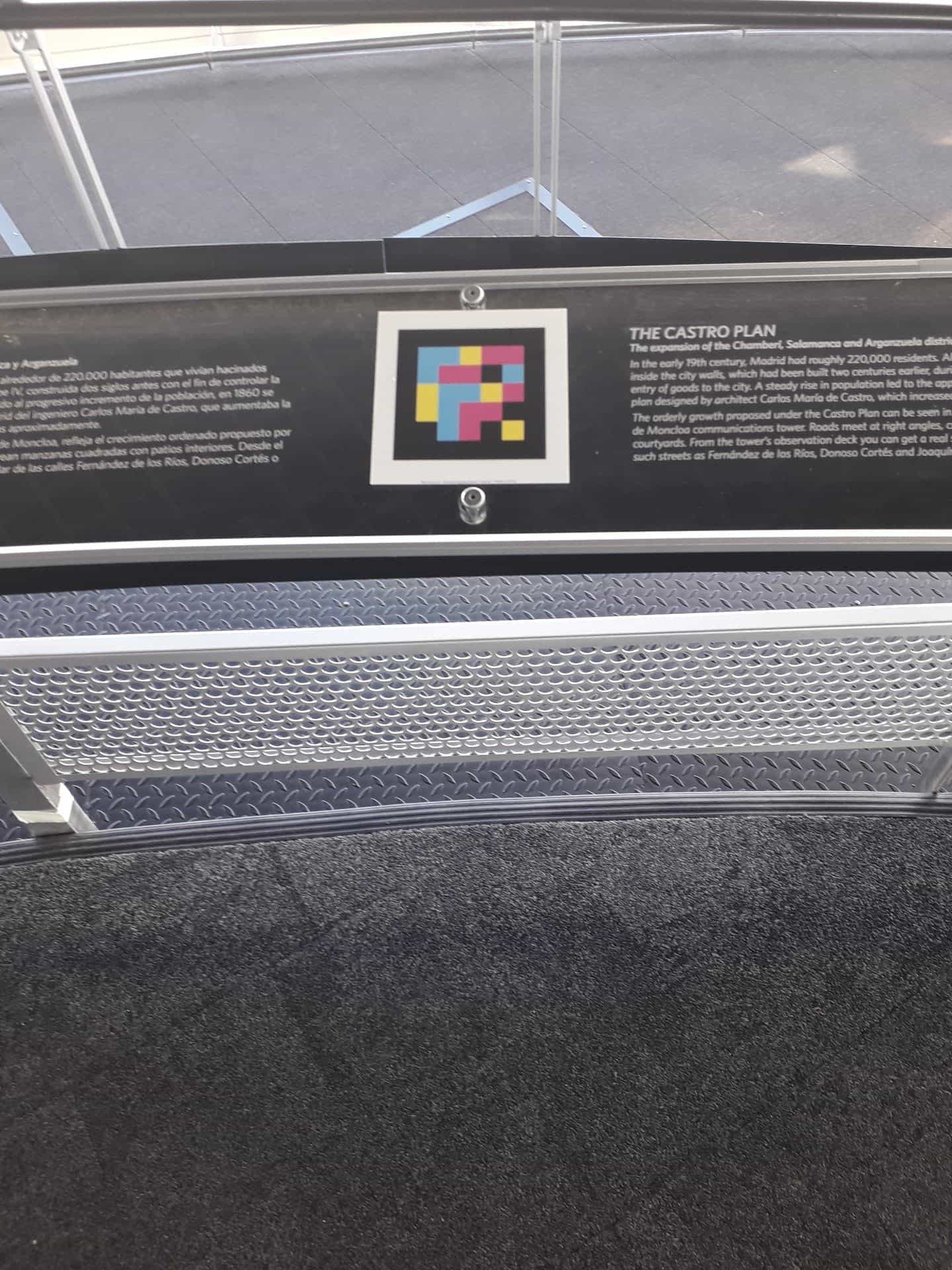 Parapetto informativo del belvedere del Faro de Moncloa: sopra un pannello nero che spiega «The Castro Plan» in spagnolo e in inglese, un codice NaviLens quadrato a colori con cornice bianca permette di ascoltare il contenuto del pannello dal telefono