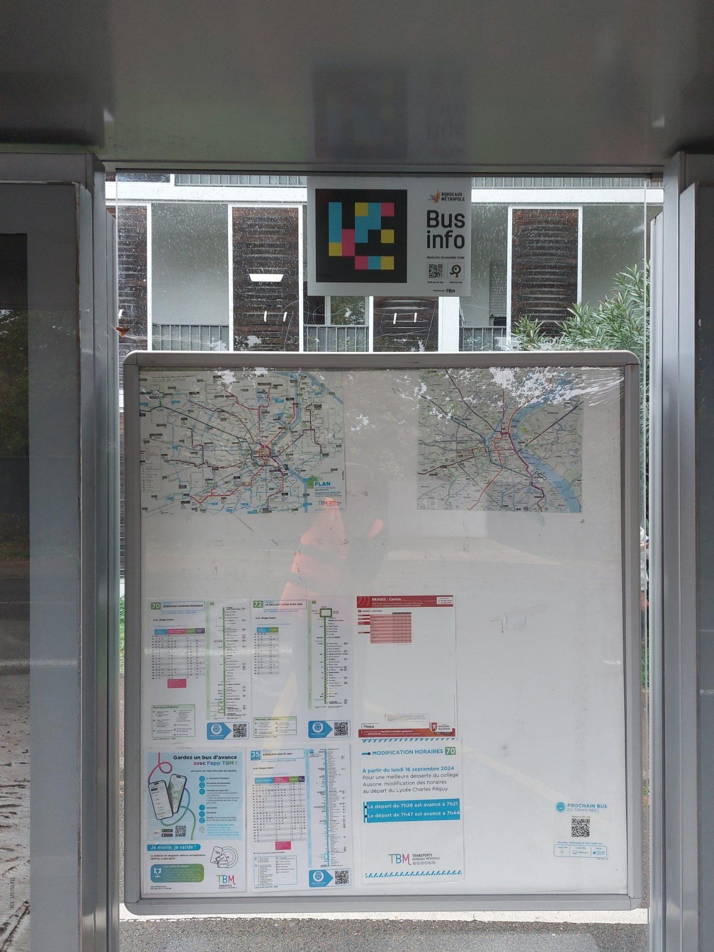 Panel «Bus info — NaviLens Accessible Code» con el código de colores instalado sobre el plano de red dentro de una marquesina TBM en Bruges Centre