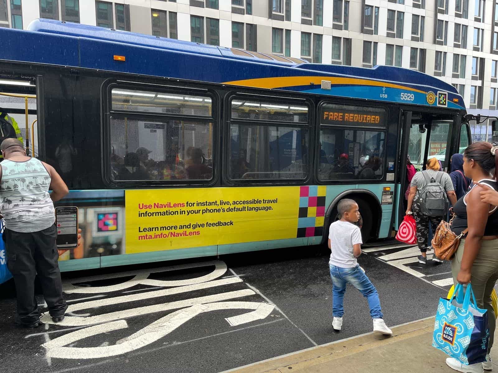 Fianco del bus MTA 5529 con pubblicità istituzionale gialla: «Use NaviLens for instant, live, accessible travel information in your phone’s default language. Learn more and give feedback — mta.info/NaviLens»