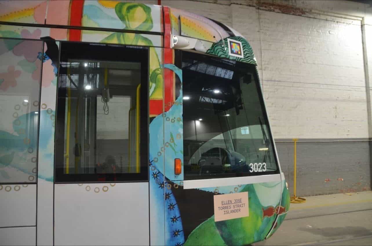 ヤラ・トラムの Alstom 製 C-Class 3023 の前面。Ellen José（トレス海峡諸島出身)のアートを纏った Art Tram で、白地に緑・青・赤の水彩。運転台上に白枠の NaviLens コード、前照灯の下に「ELLEN JOSÉ — TORRES STRAIT ISLANDER」の小さなプレート