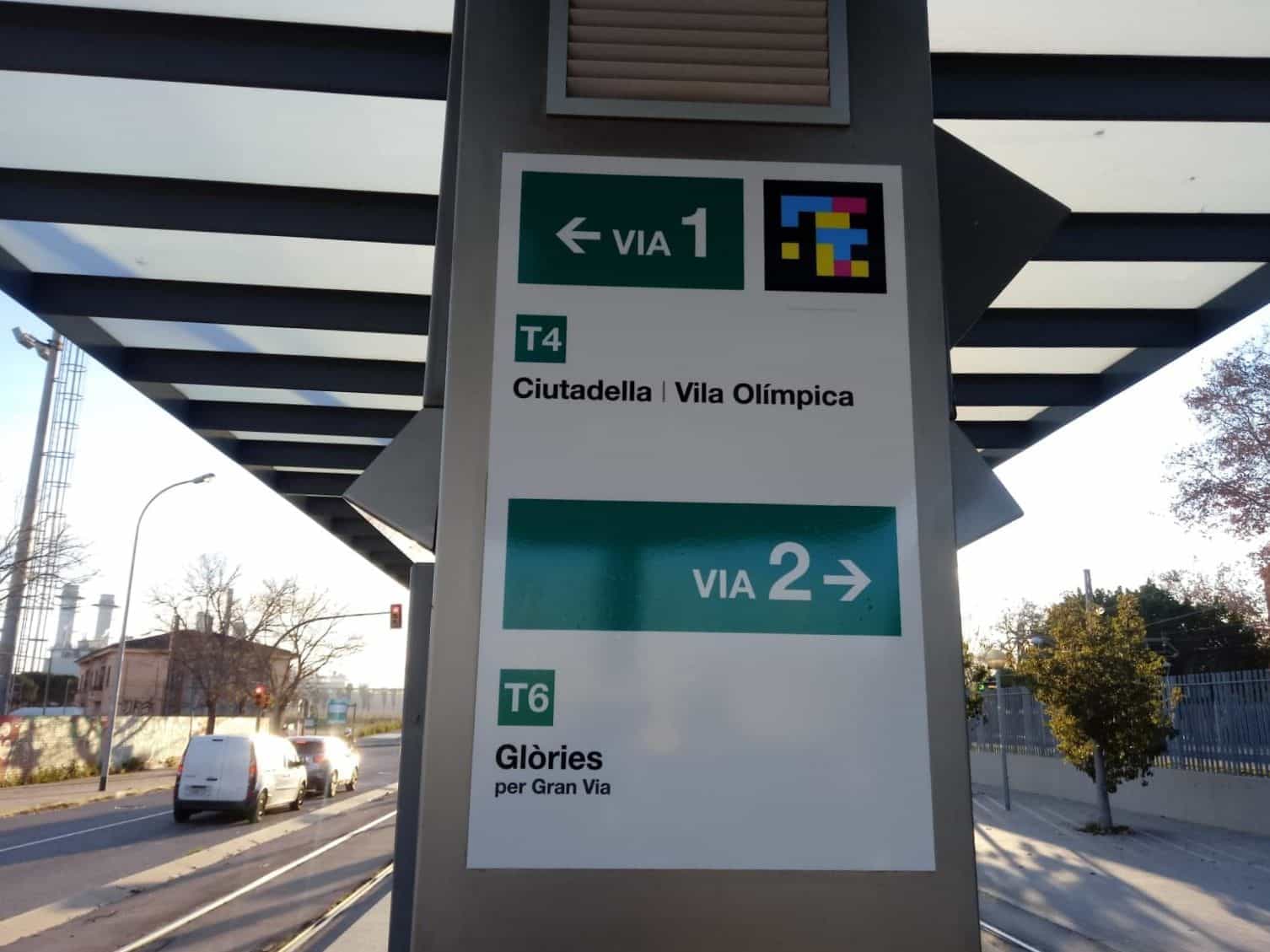 Beidseitiges Schild: Gleis 1 ← T4 Ciutadella | Vila Olímpica und Gleis 2 → T6 Glòries per Gran Via mit NaviLens-Code