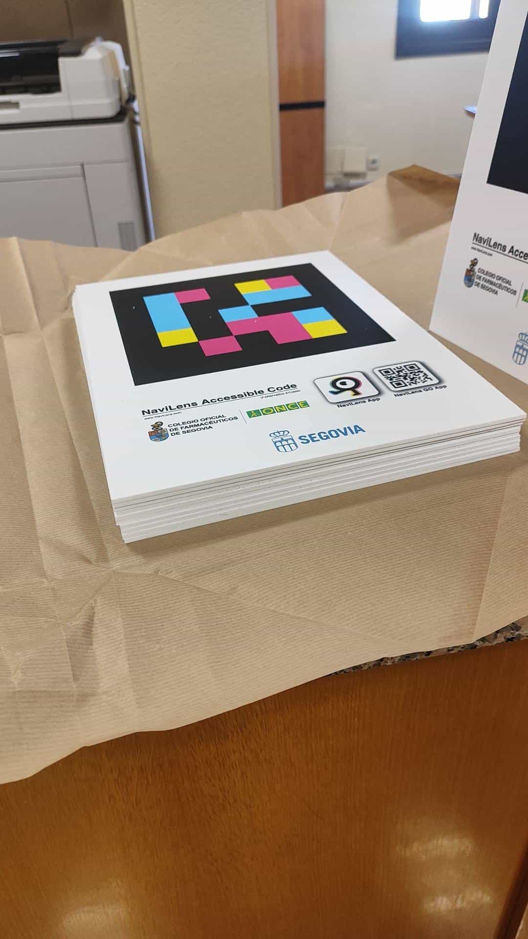 Stack of freshly printed NaviLens signs with the Segovia COF, ONCE and City Council logos, ready to be distributed