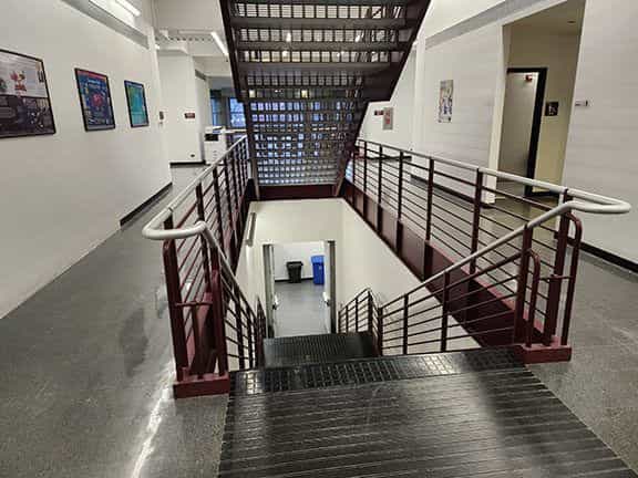 Zentrale Treppe eines akademischen Gebäudes der NIU mit roten Geländern, Aufsicht auf den Treppenabsatz und gerahmten Schildern in den Fluren