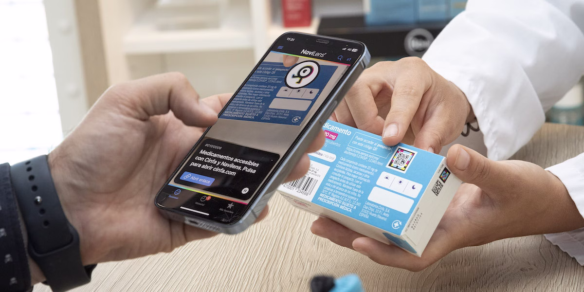 Ilustración de un cartonaje de medicamento de Cinfa con un código NaviLens y una mano sujetando un smartphone con la app NaviLens GO.