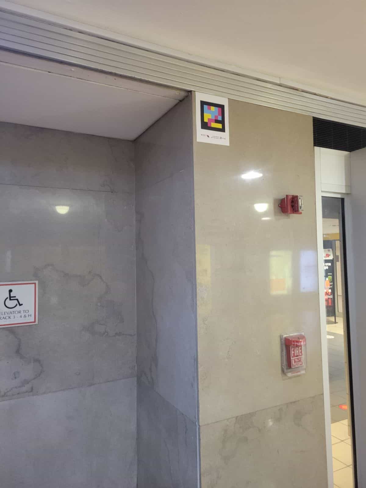 Código NaviLens instalado en alto sobre el corredor de ascensores hacia las vías 3-4 y H en el interior de Newark Penn Station