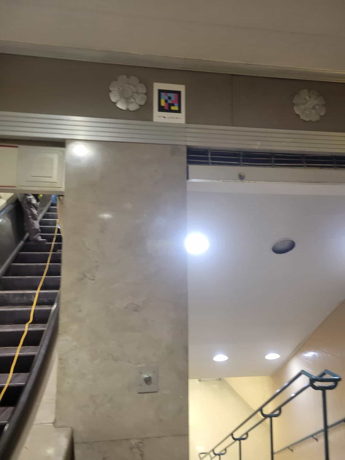 NaviLens code fixed on the wall between two decorative rosettes, above the escalators of the Newark Penn Station main hall