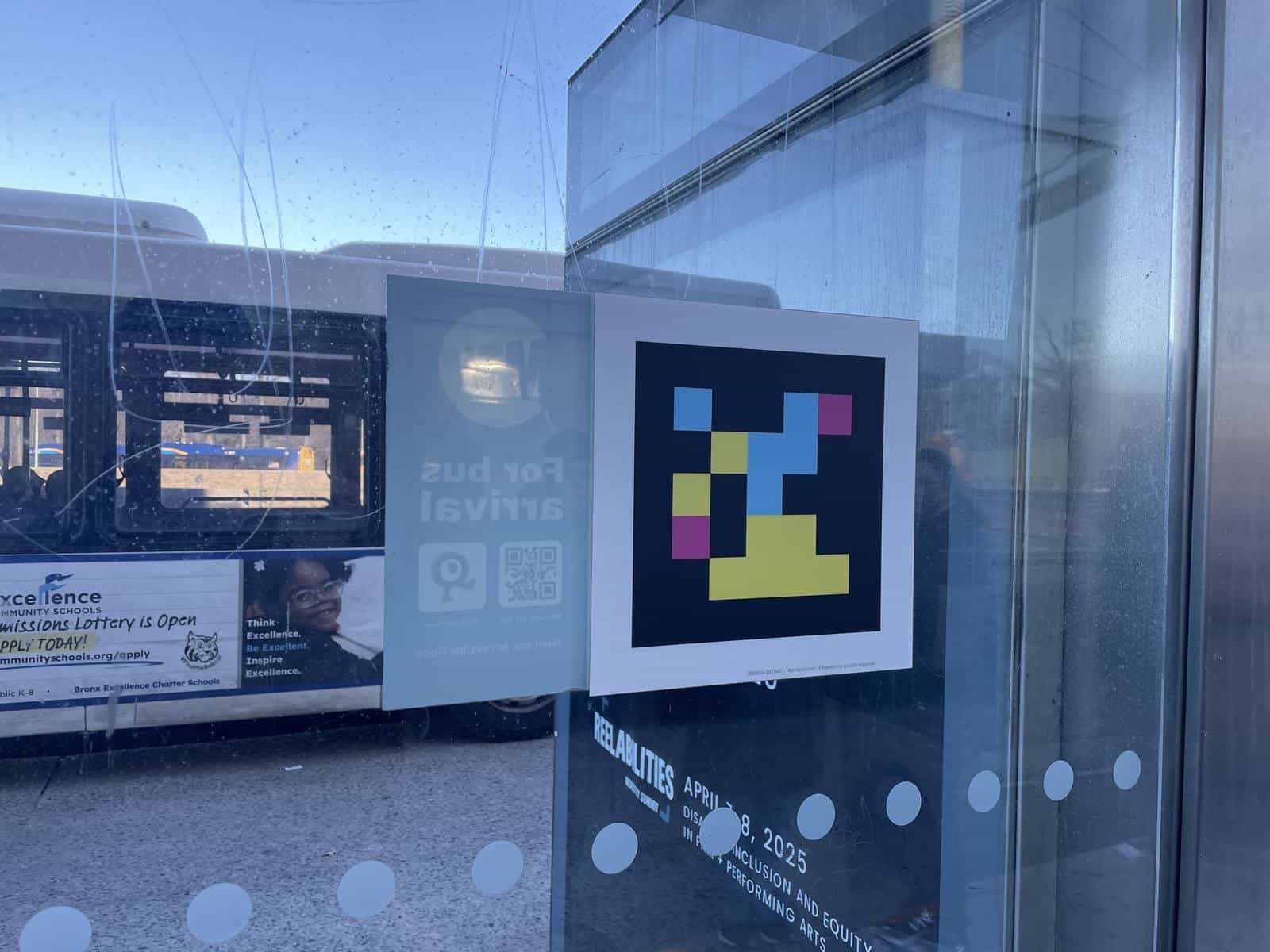 NaviLens code printed on the glass of a Bronx shelter, right beside the MTA “For bus arrival” panel, with a bus stopped behind