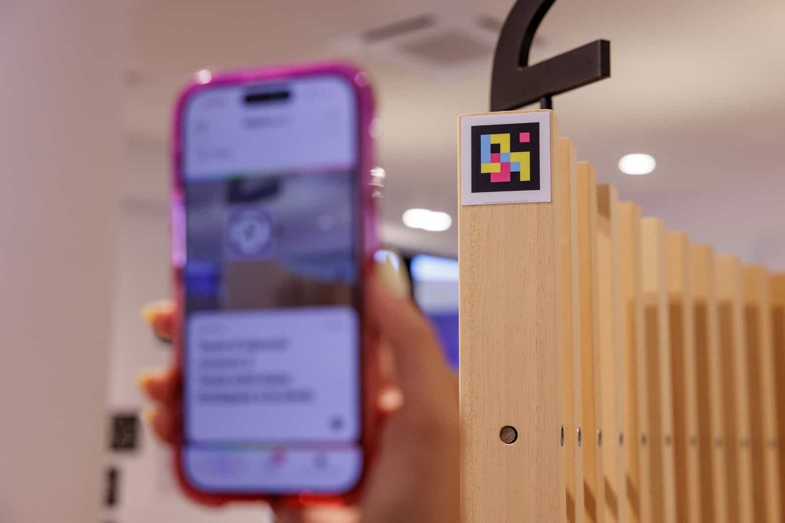 Aigües de Barcelonaの窓口で、NaviLensアプリが3番窓口を読み上げているスマートフォンを手に持つ様子。