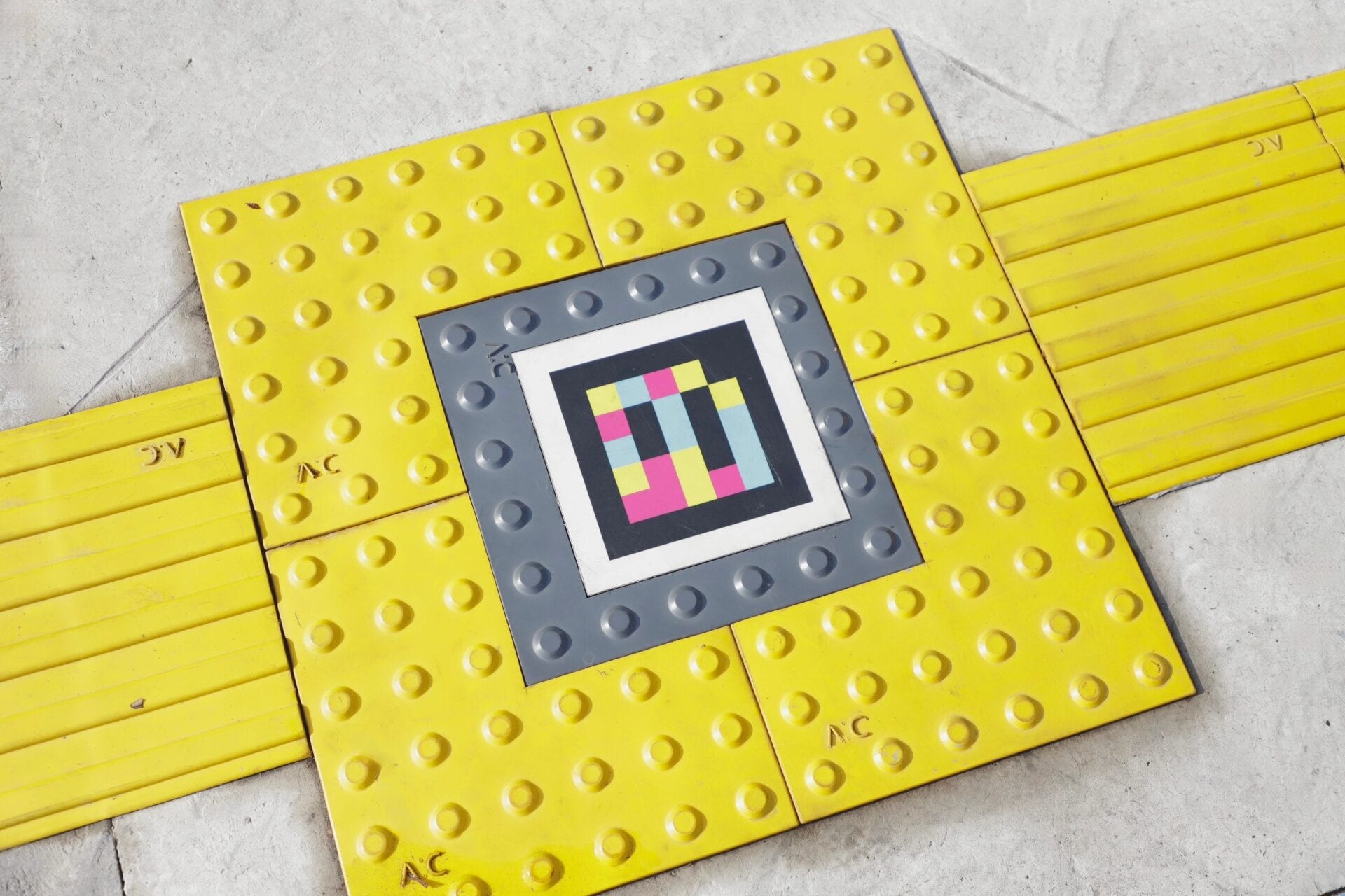 NaviLens code framed at the centre of a yellow cross-shaped tactile paving mosaic on the floor at the entrance to the Zapopan Passport Office