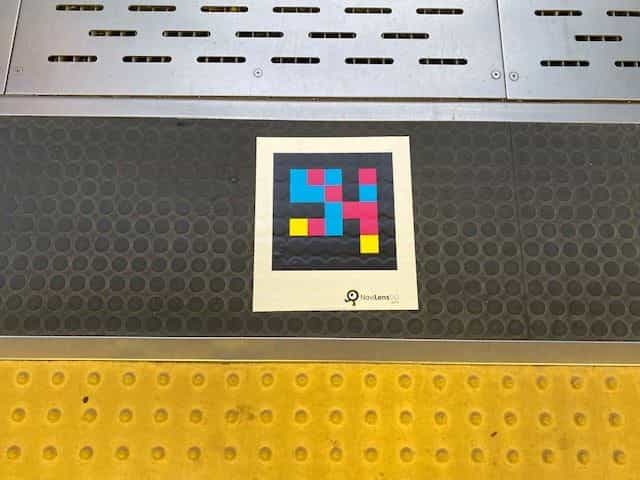 ポートライナーのホーム床面、黄色い点字ブロック(警告ブロック)の縁に置かれた白いカードに印刷されたNaviLens GOタグ