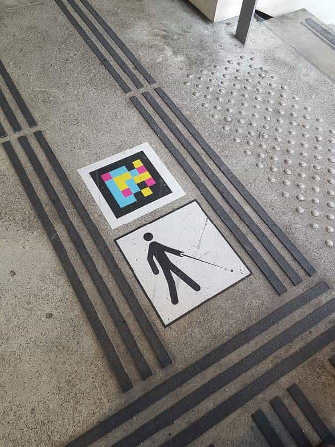 Floor detail at Versailles-Chantiers: tactile strips around a NaviLens code and pictogram of a person with a cane