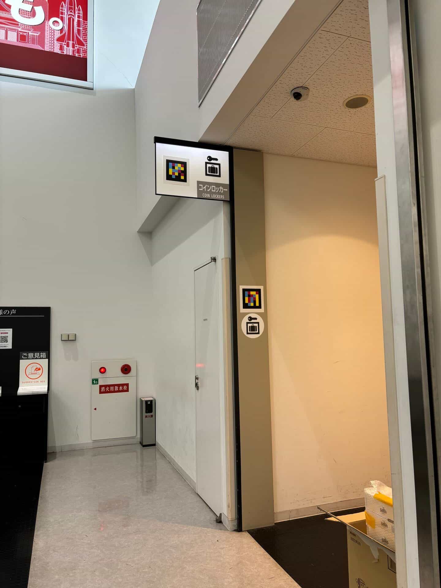 Seitlicher Gang im Kobe Airport zum Eingang der Schließfächer: zwei NaviLens-Tags auf unterschiedlichen Höhen