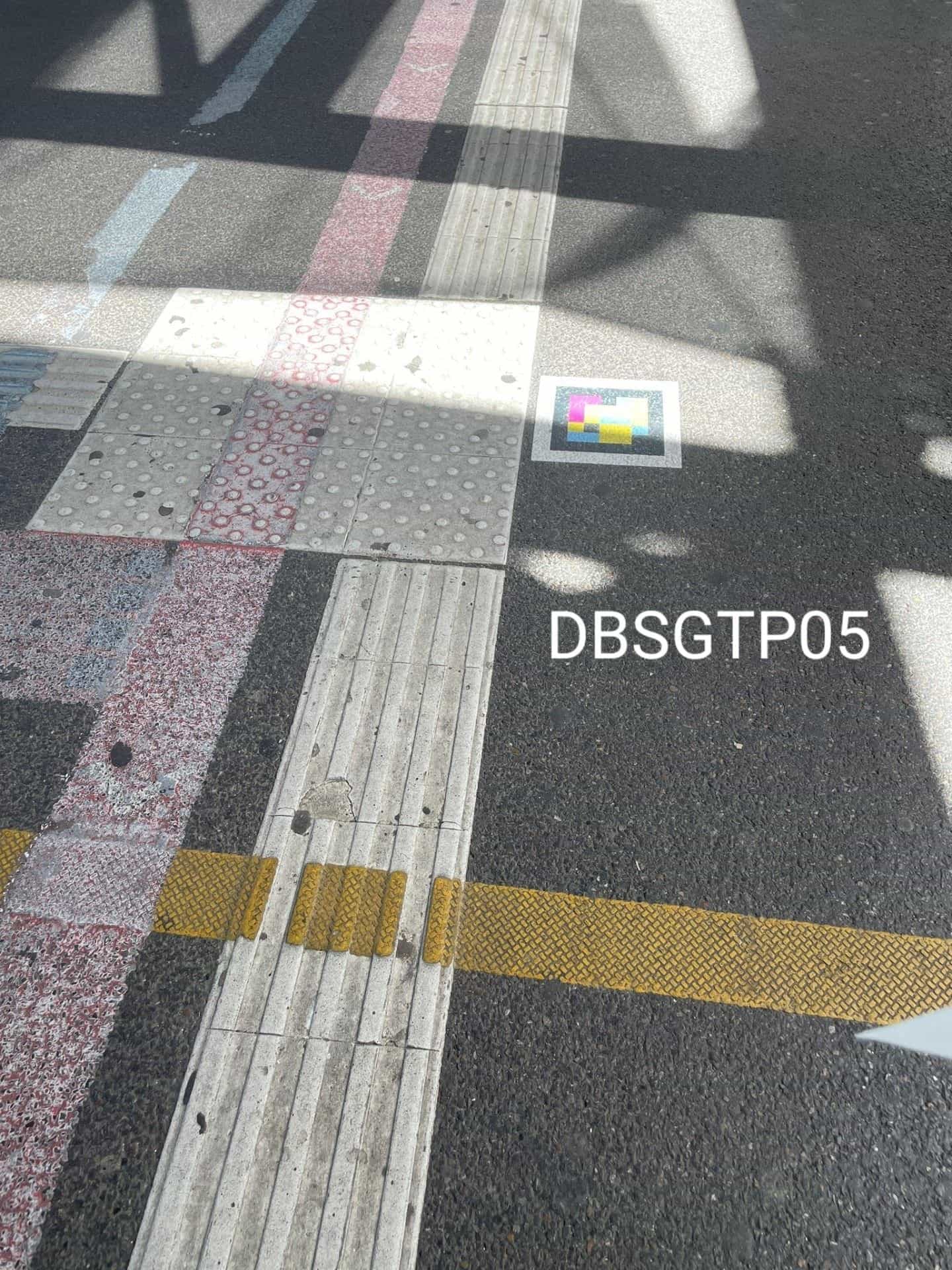 Sol d’un passage piéton près du Hbf de Stuttgart avec dalles podotactiles et code NaviLens collé près de la bordure (DBSGTP05)
