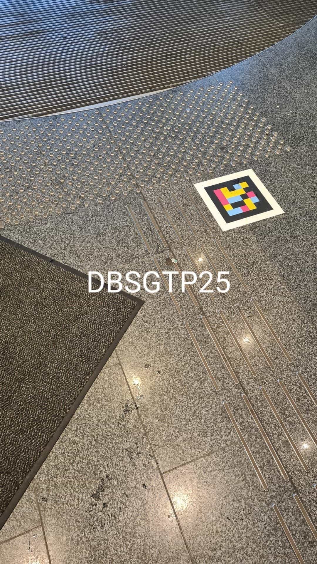 Detail des polierten grauen Granitbodens im Inneren der Klett-Passage: in den Belag eingelassene metallene Leitstreifen führen zu einem NaviLens-Code neben einem Bereich mit taktilen Noppen