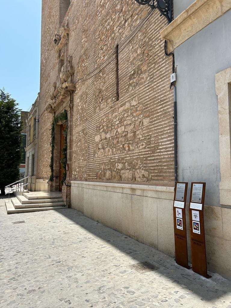 Cobbled street in Silla with two corten-steel totems aligned next to the side of the Church of the Virgin of the Angels.