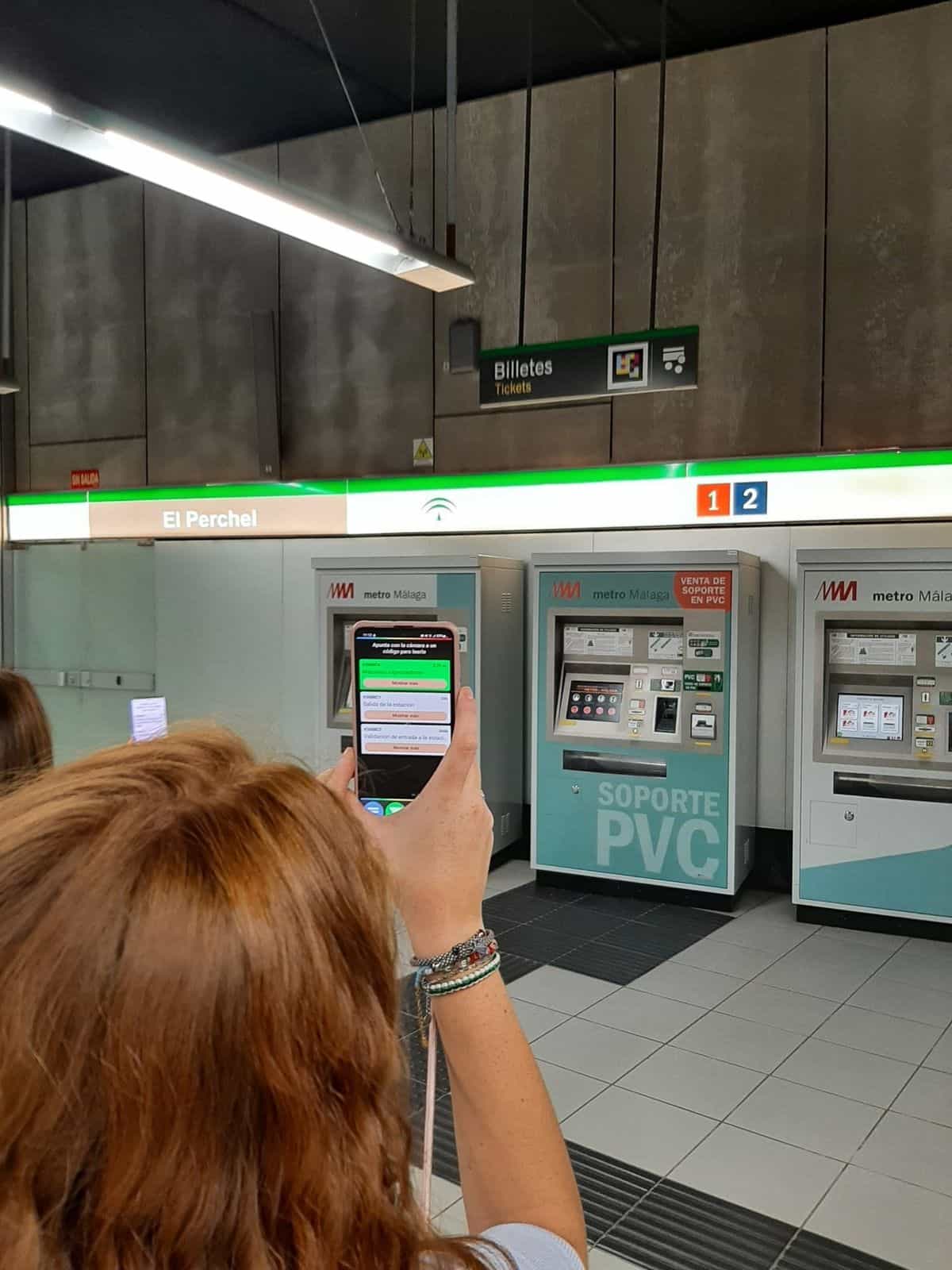 Vestíbulo de El Perchel: usuaria escanea con su smartphone el cartel «Billetes / Tickets» con código NaviLens