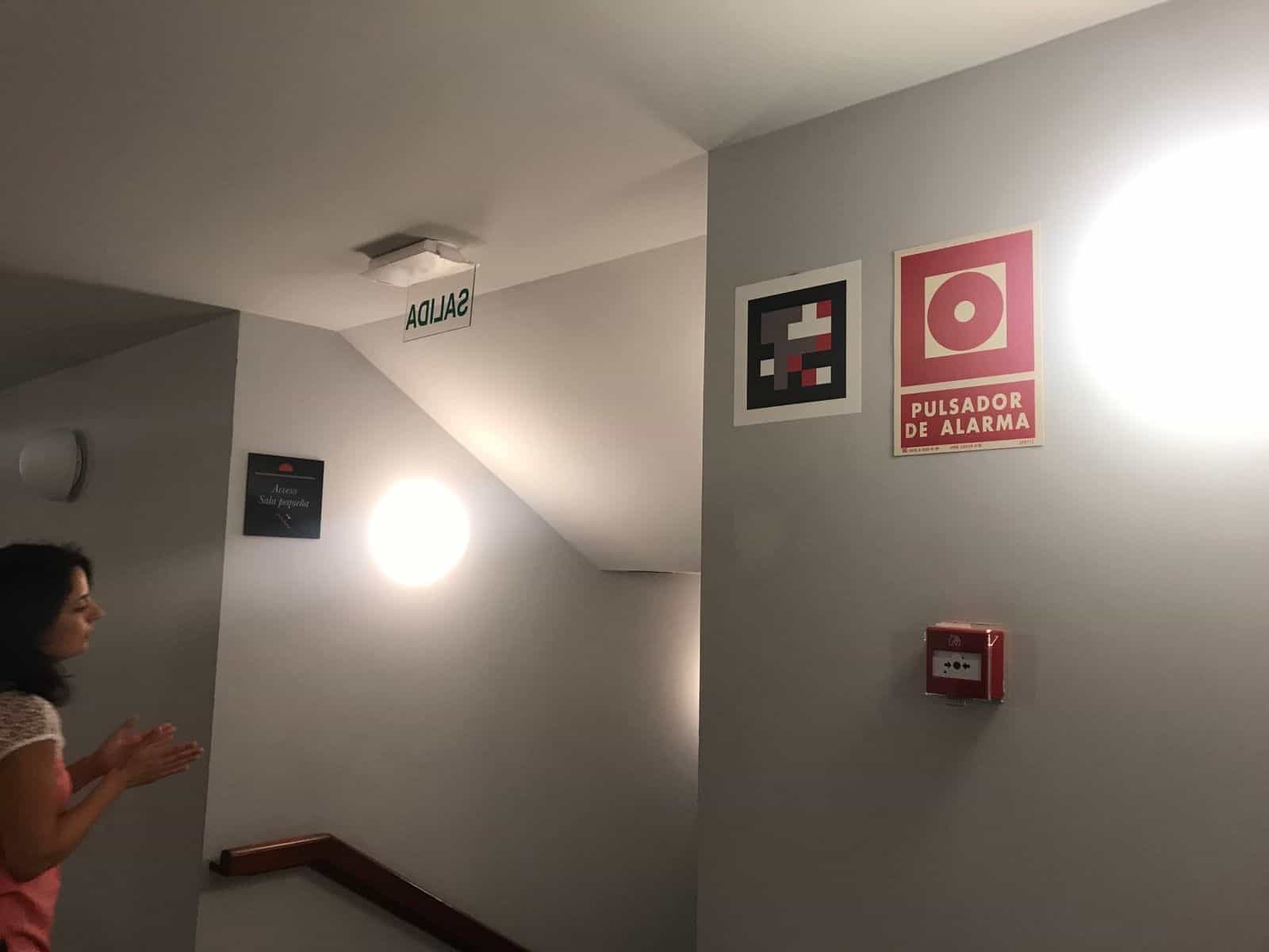Scala di uscita del Teatro Circo con segnale di emergenza e codice NaviLens accanto al pulsante di allarme
