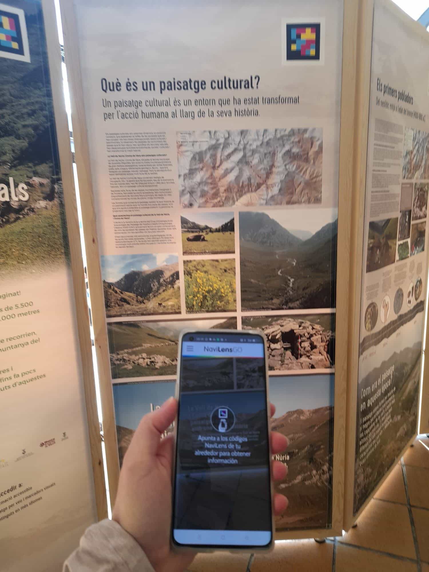 Visitatore che punta NaviLens GO verso il codice del pannello «Què és un paisatge cultural?» nella mostra dell’ICAC nella Vall de Núria