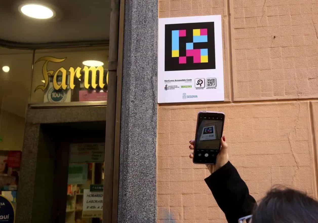 Person scannt mit dem Handy ein NaviLens-Schild der Segovianer Apothekerkammer an einer Apothekenfassade