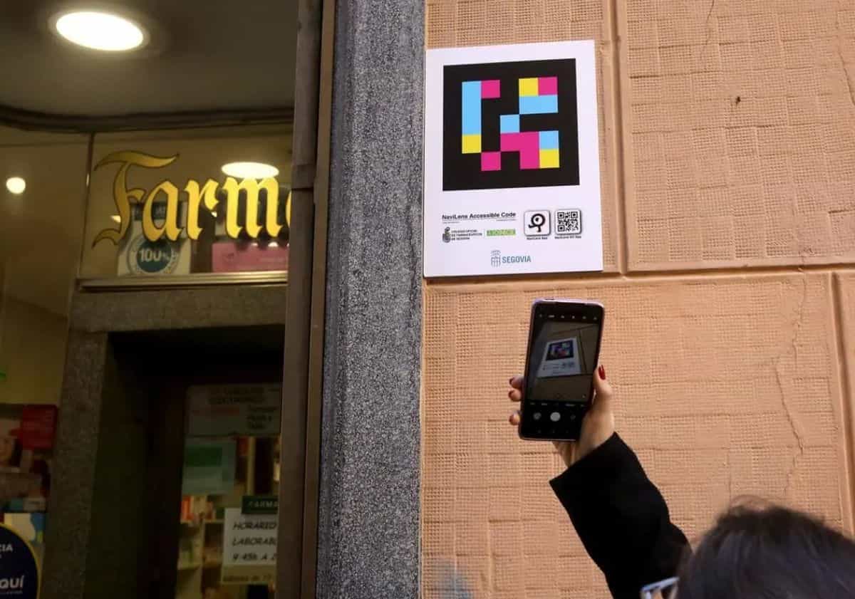 Person scannt mit dem Handy ein NaviLens-Schild der Segovianer Apothekerkammer an einer Apothekenfassade