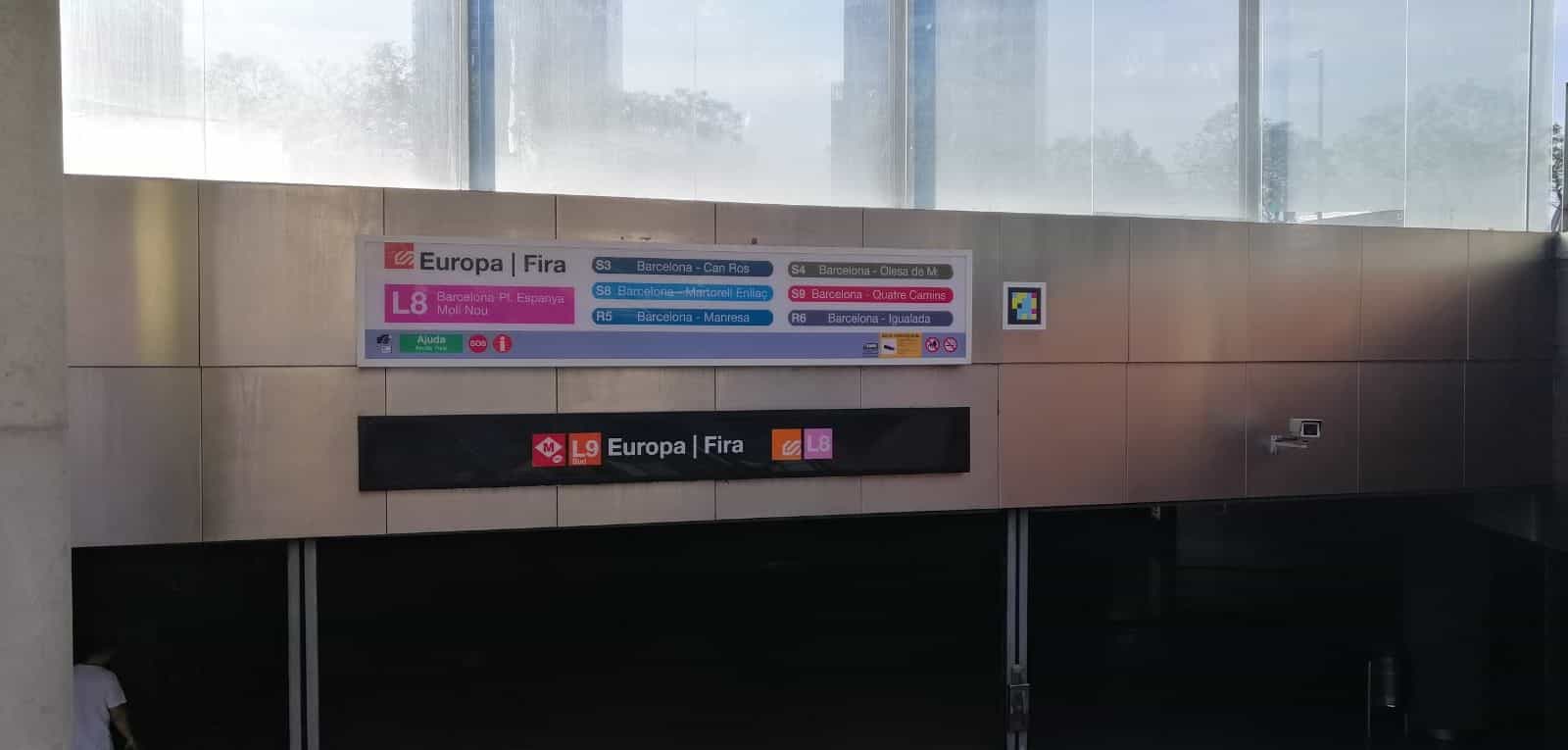 FGC Europa | Fira駅のメイン標識:L8、S3、S4、S8、S9、R5、R6の路線の横にNaviLensコード