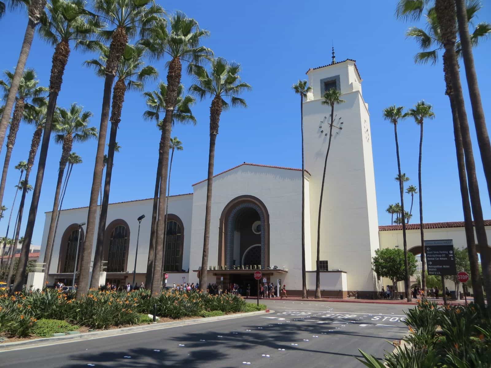 Veduta frontale dell’edificio principale della Union Station: architettura Mission Revival e Streamline Moderne con torre dell’orologio, palme alte e ingresso pedonale all’atrio storico