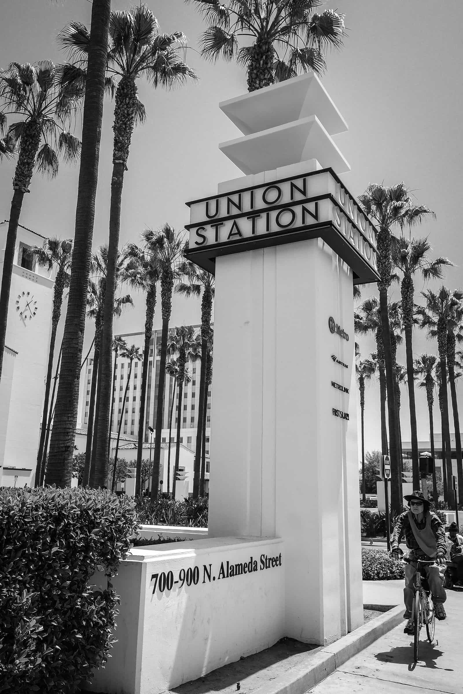 Veduta esterna della Los Angeles Union Station al tramonto: torre dell’orologio in stile Mission Revival, palme all’ingresso principale e archi dell’atrio illuminati