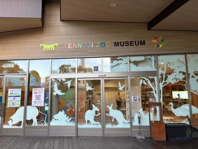Façade of the TENNOJI ZOO MUSEUM in Osaka, stained-glass windows with animal silhouettes and NaviLens posters on the door