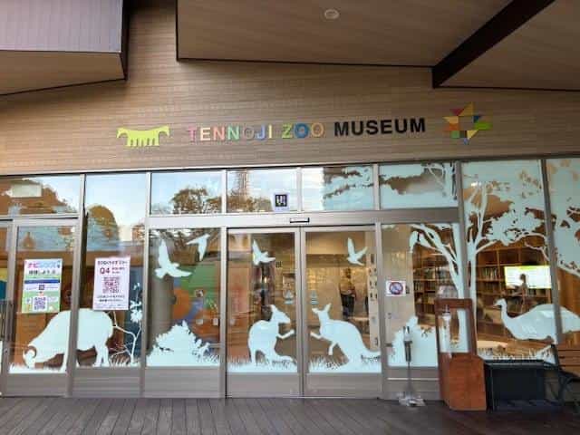 Façade of the TENNOJI ZOO MUSEUM in Osaka, stained-glass windows with animal silhouettes and NaviLens posters on the door