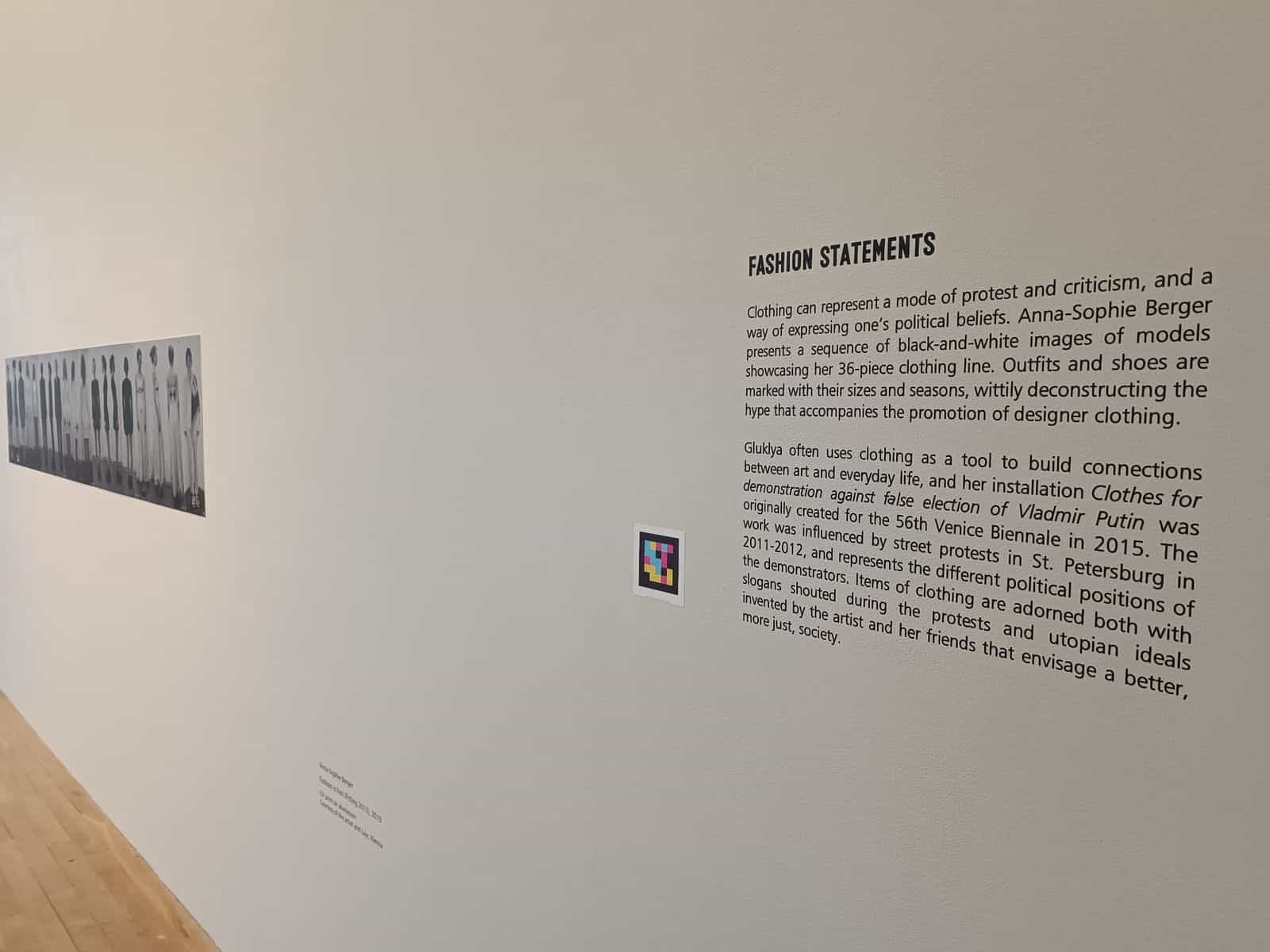 Wall of the Fashion Statements section at Fashion Show with a NaviLens code next to text about Anna-Sophie Berger and Gluklya, in front of a black and white photographic series