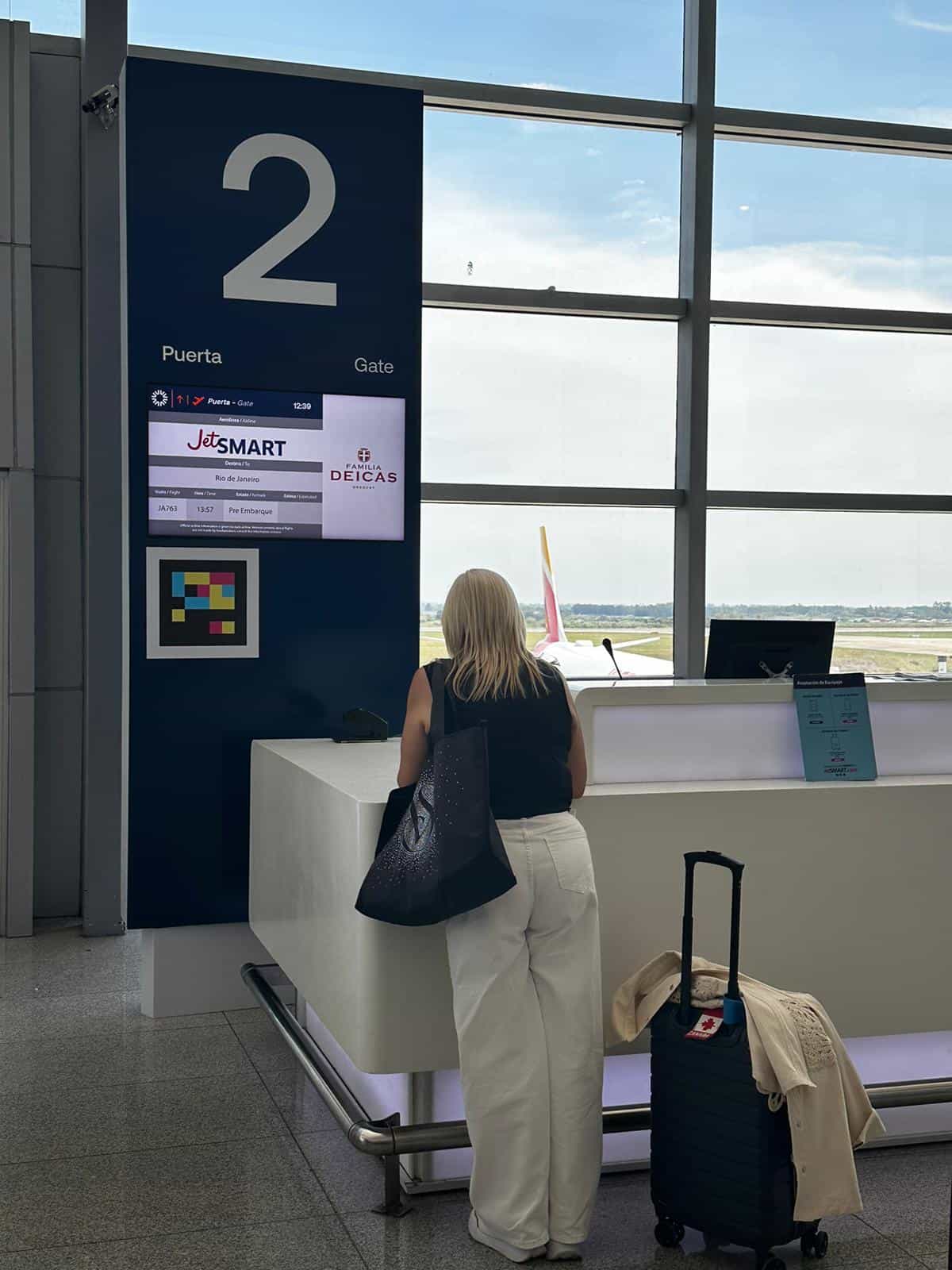Pasajera consultando información de vuelo junto a señalización NaviLens en una terminal aeroportuaria