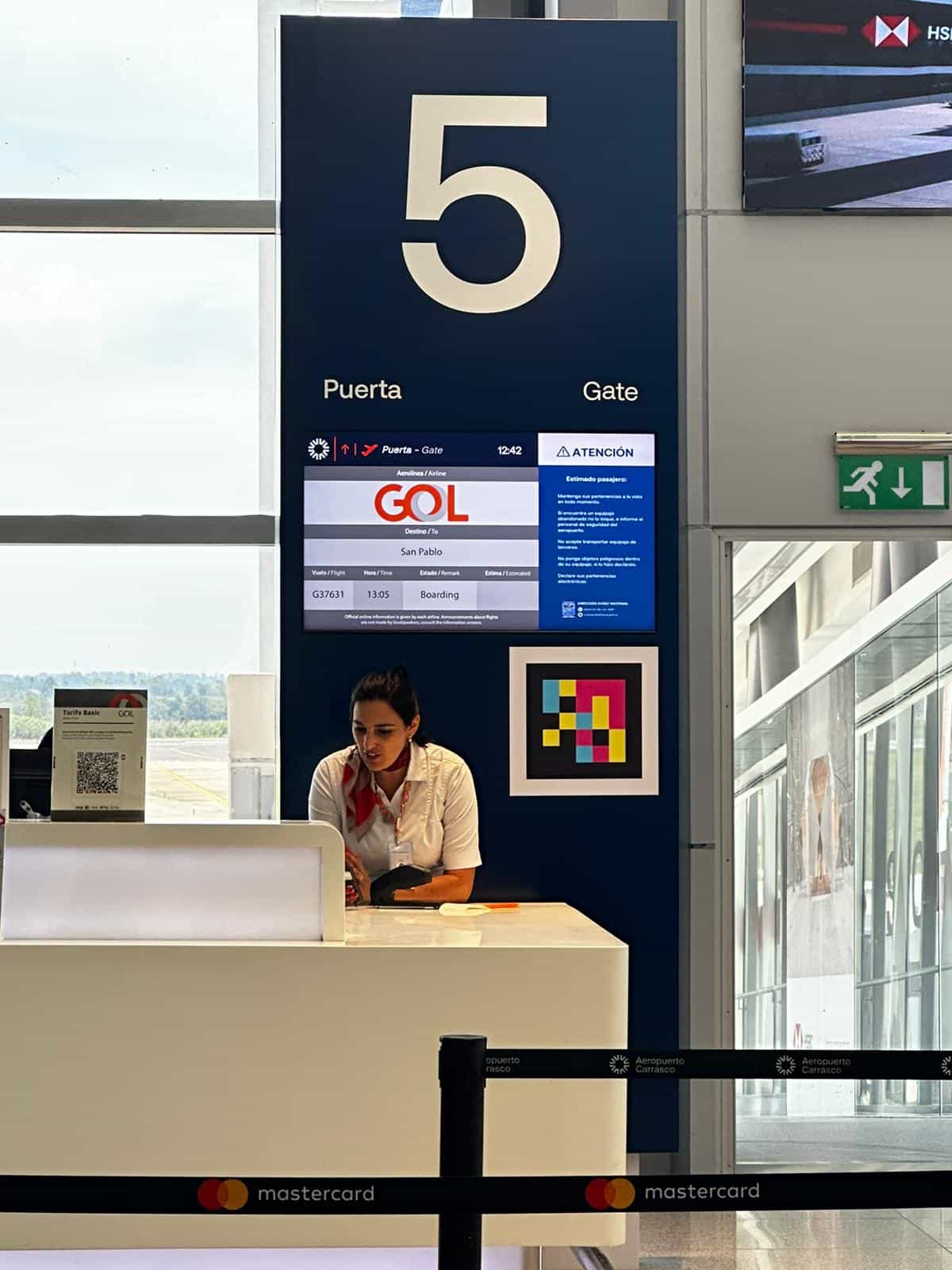 Pantalla FIDS de la Puerta 5 del Aeropuerto de Carrasco con el vuelo de GOL a San Pablo y un código NaviLens detectable a varios metros