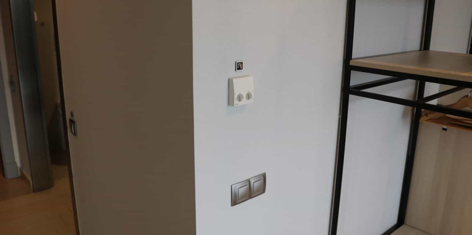 Thermostat und Schalter an der Innenwand eines Zimmers im AR Diamante Beach, mit kleinem NaviLens-Code neben dem Thermostat