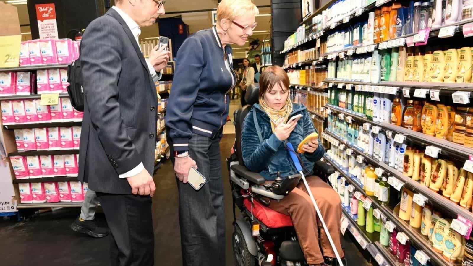 Ein Kunde im Rollstuhl scannt ein Körperpflegeprodukt bei Carrefour Auderghem