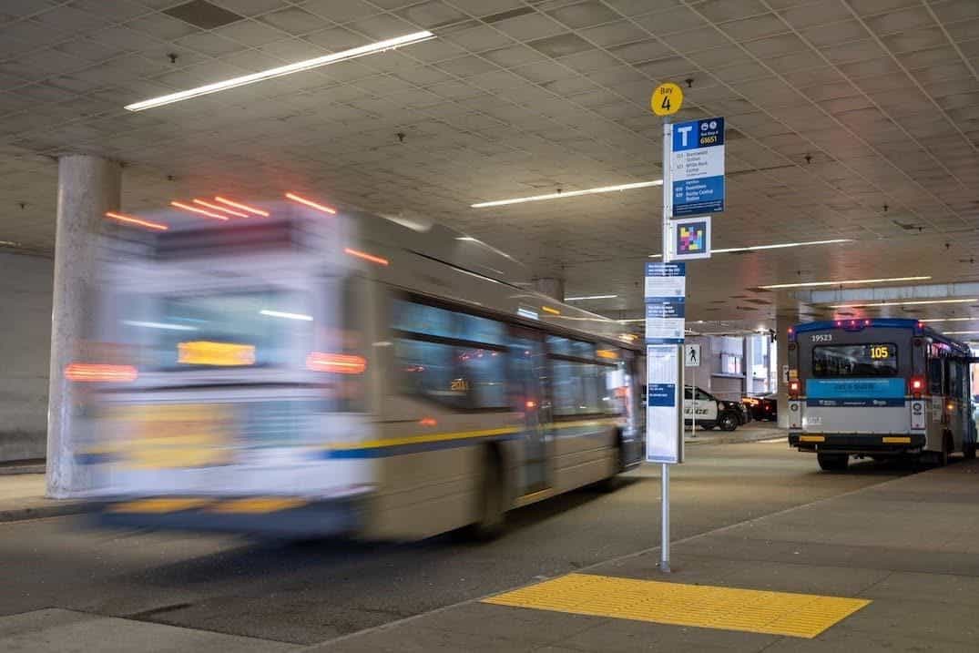 Busbahnhof mit NaviLens-Code an der Säule von Bay 4 und vorbeifahrendem Bus